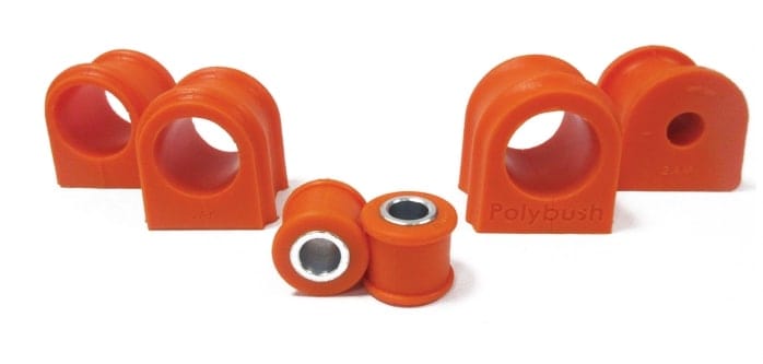 A set of orange polybush brand car suspension bushings, including two larger d-shaped and two smaller cylindrical pieces with metal inlays, displayed against a white backdrop.