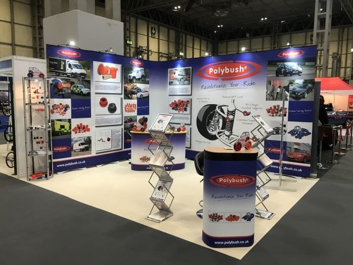 Exhibition stand for polybush featuring informational displays, promotional materials on desks, a distinctive blue and red design theme, and various images of car parts.