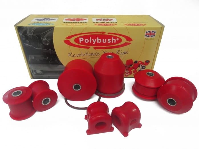 Various red polybush car suspension parts displayed in front of their packaging box, which features the brand logo and the union jack flag.