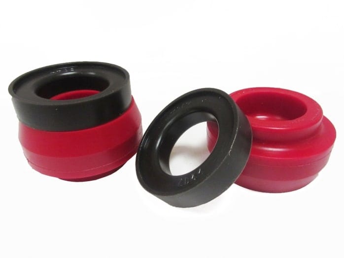 Three skateboard wheels arranged on a white surface, two of which are red with black centres and one solid black.